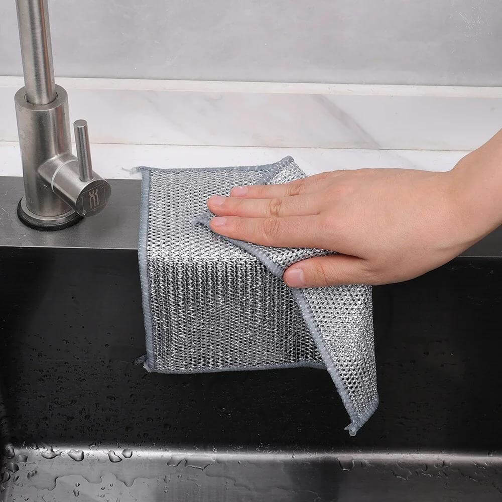 12pcs non-stick oil iron dishwashing cloth being used to clean a kitchen sink, showcasing its practical use in a modern setting.
