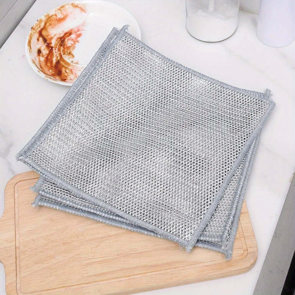 Stack of 12pcs non-stick oil iron dishwashing cloths on a wooden cutting board in a kitchen setting.