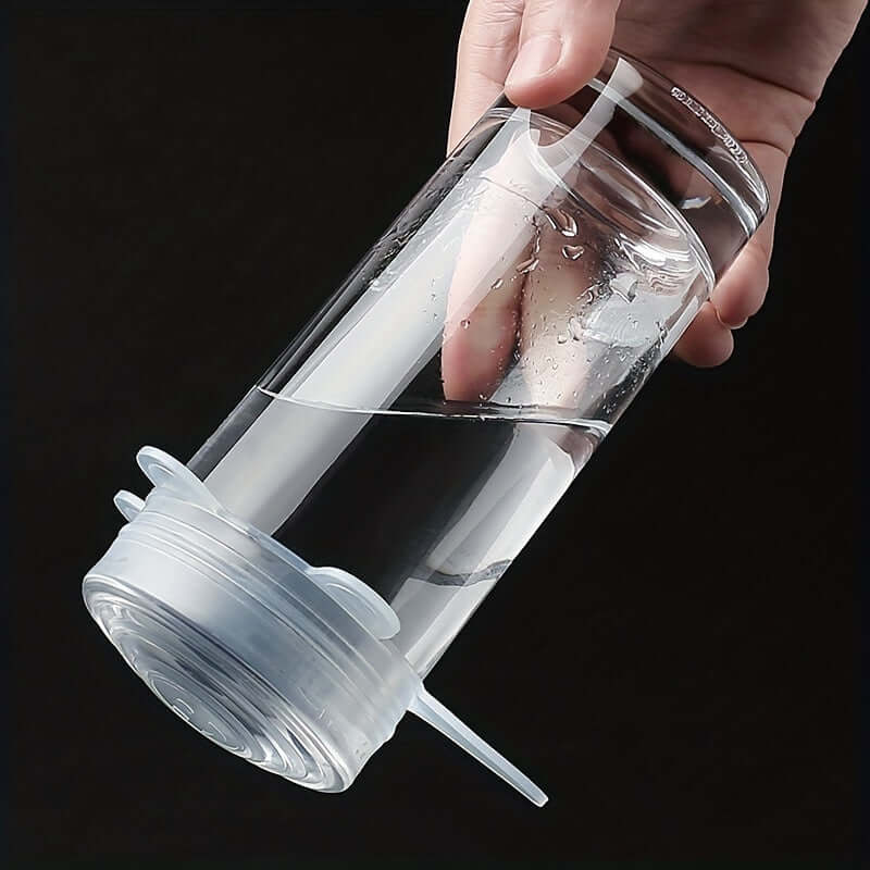 Person holding a clear glass with silicone lid, demonstrating reusable Flexilids for food covers.