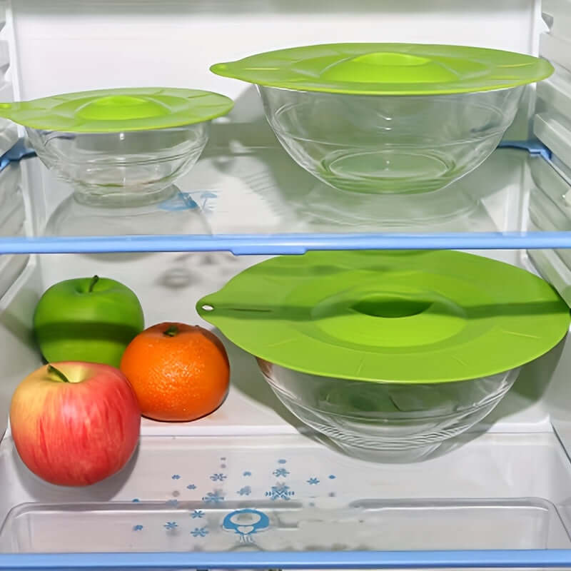 Silicone bowl lids in a refrigerator covering glass bowls, showcasing heat resistant silicone material. Perfect for food storage.