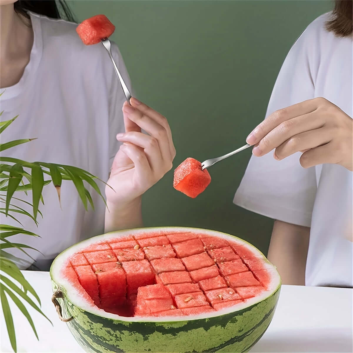 Two hands using a stainless steel watermelon slicer to serve perfect cubes of watermelon from a beautifully cut melon.