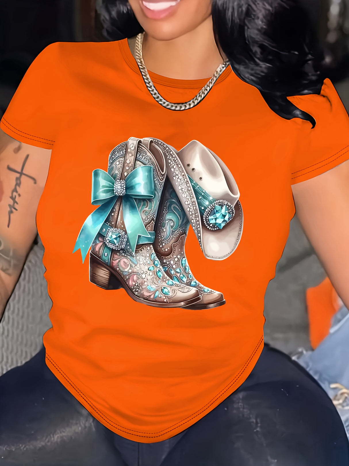 Stylish orange t-shirt featuring decorative cowboy boots with a bow and bling, perfect for casual wear.