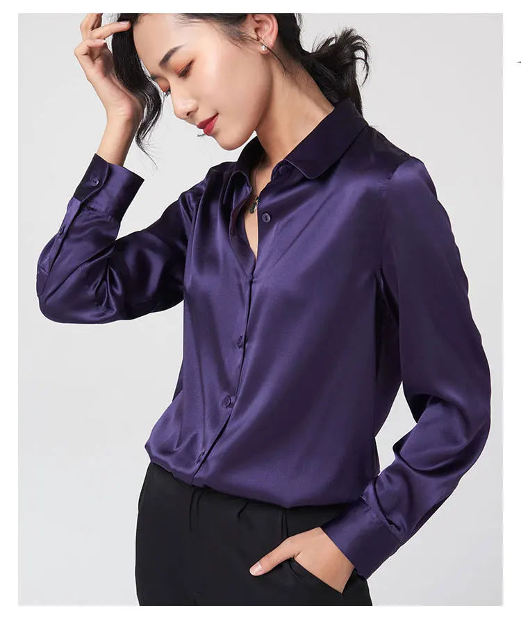 Model wearing a purple satin long sleeve silk blouse with a V-neck collar and single breasted closure.