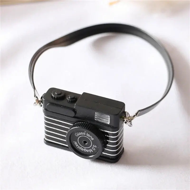 Black mini camera for dollhouse photography, ideal baby photo props, made of plastic and electronics.