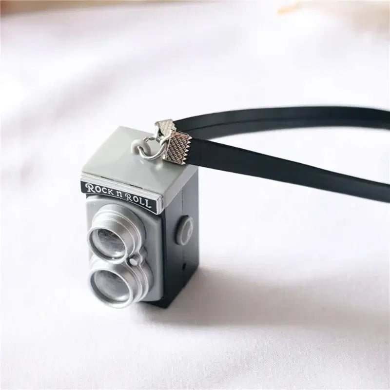 Miniature black and gray camera keychain for dollhouse, ideal for baby photography props and photo gifts.