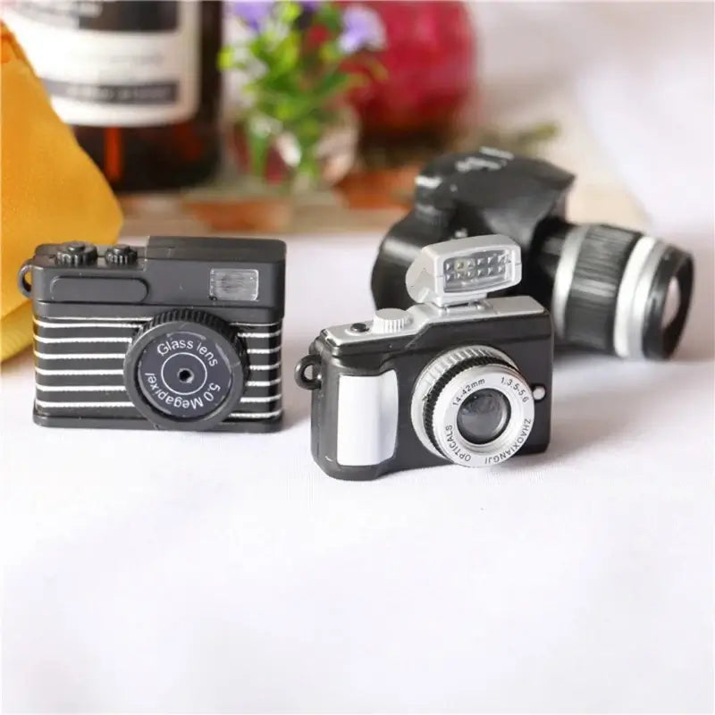 Miniature black cameras for dollhouse photography, perfect baby photo props, designed for ages 0-12 months.