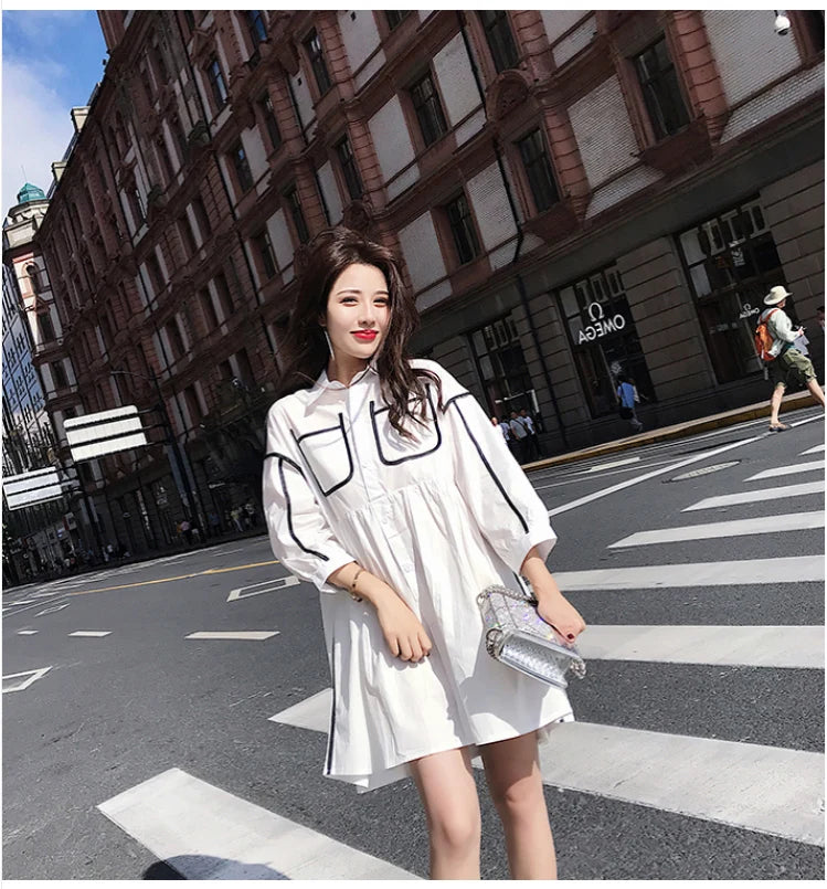 Woman wearing a solid color maternity shirt dress with pockets, styled for a summer beach party.