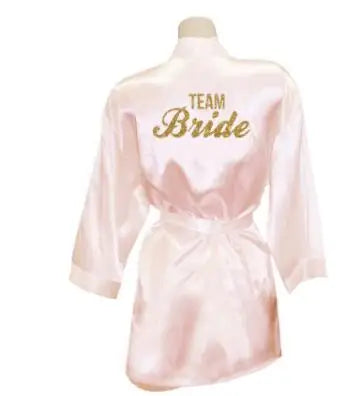 Light pink satin bridesmaid robe with gold 'Team Bride' lettering, perfect for wedding celebrations.