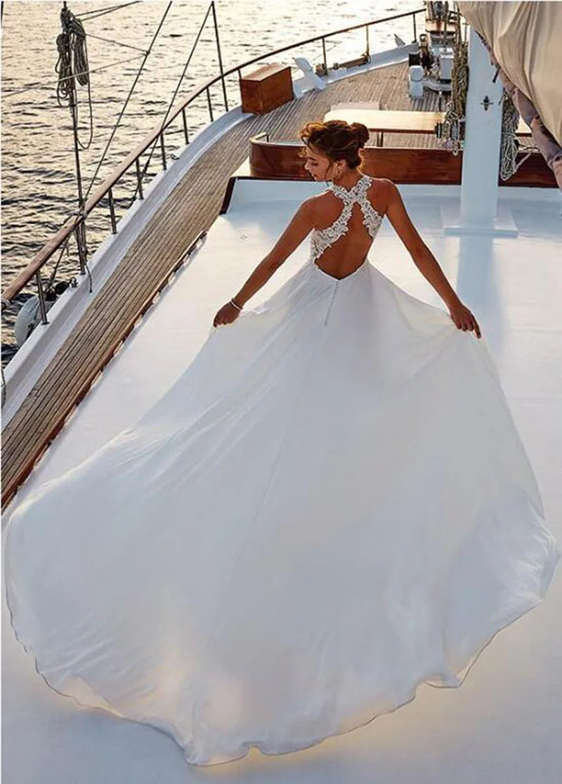 Back view of a bride in a beach satin halter wedding dress with lace appliques, flowing fabric, on a yacht.