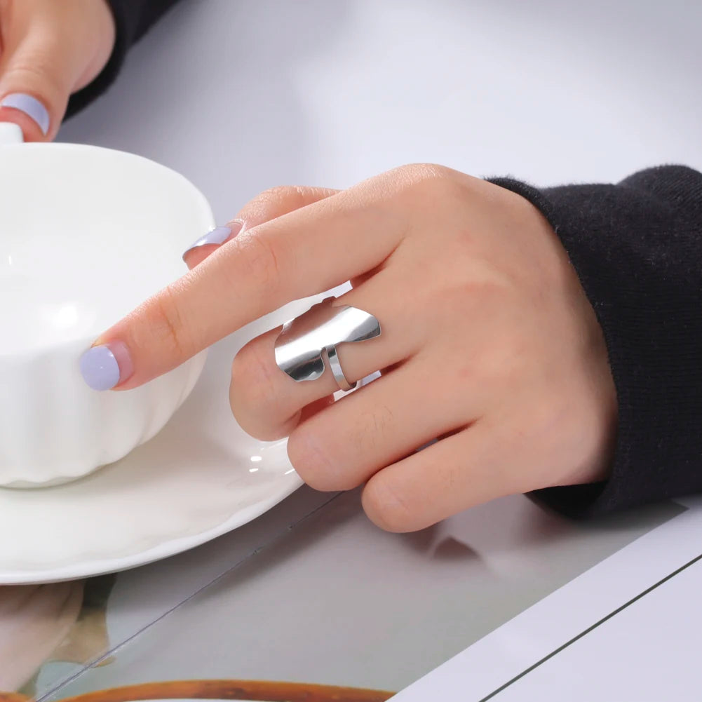 Elegant stainless steel ring worn on a woman's hand, holding a cup in a stylish setting.