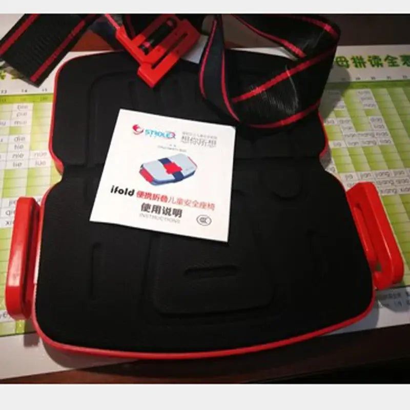 Minifold Portable Baby Car Seat Safety with adjustable straps and instructional booklet on a table