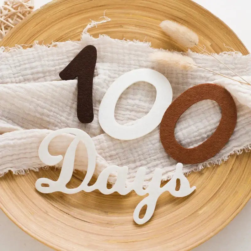 Baby milestone cards featuring soft felt '100 Days' numbers on a textured fabric background