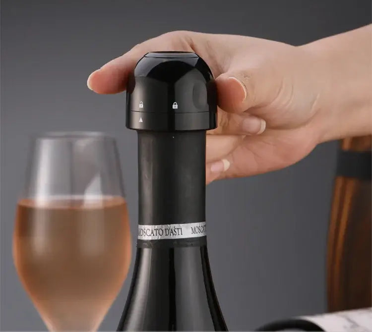 Hand placing a silicone vacuum wine bottle cap stopper on an open wine bottle next to a glass of wine.