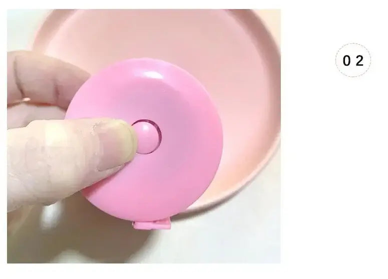 Close-up of a hand holding a pink mini height ruler next to a round pink plate, showcasing its usability for measuring.