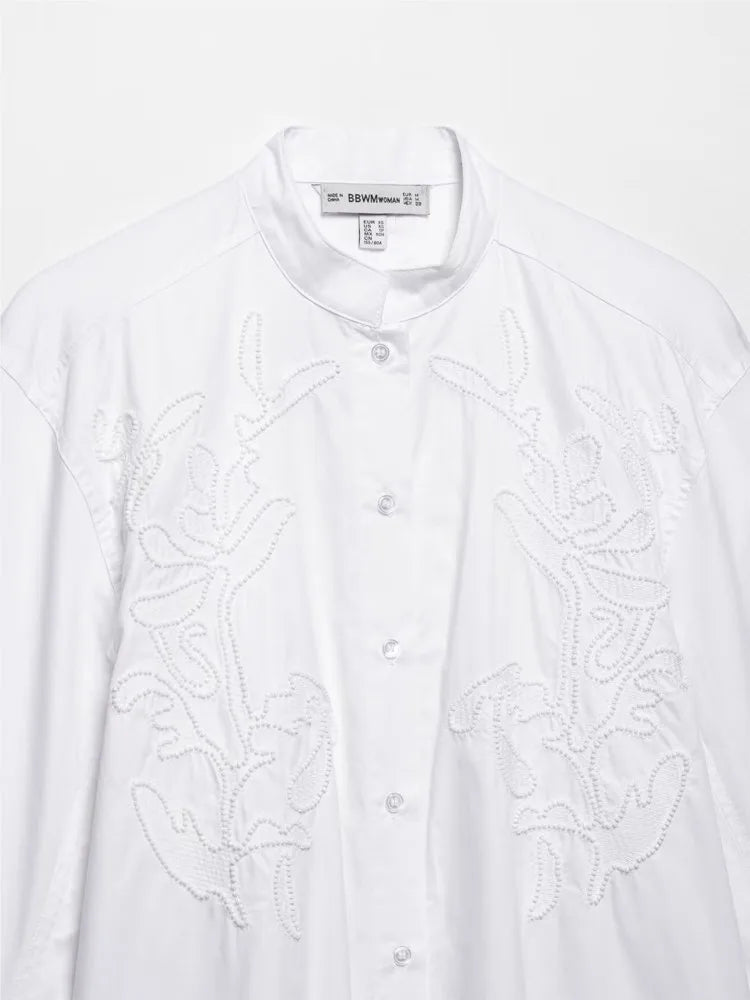 Elegant white embroidery shirt with stand collar and button closure, showcasing intricate floral designs.