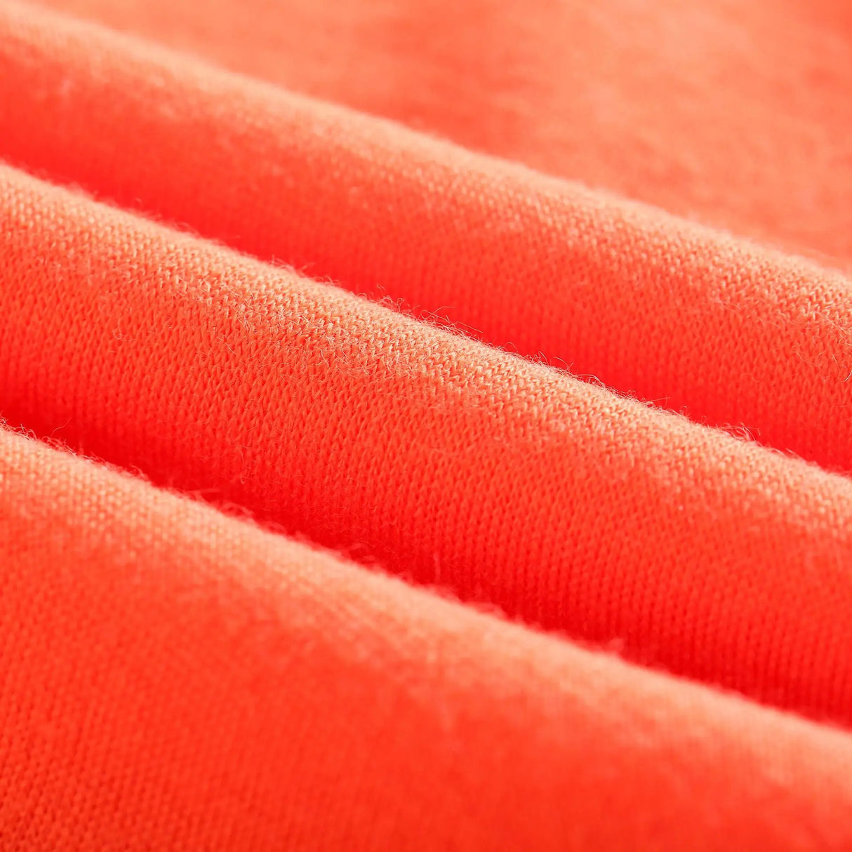 Close-up of soft, vibrant coral fabric showcasing texture, ideal for clothing.