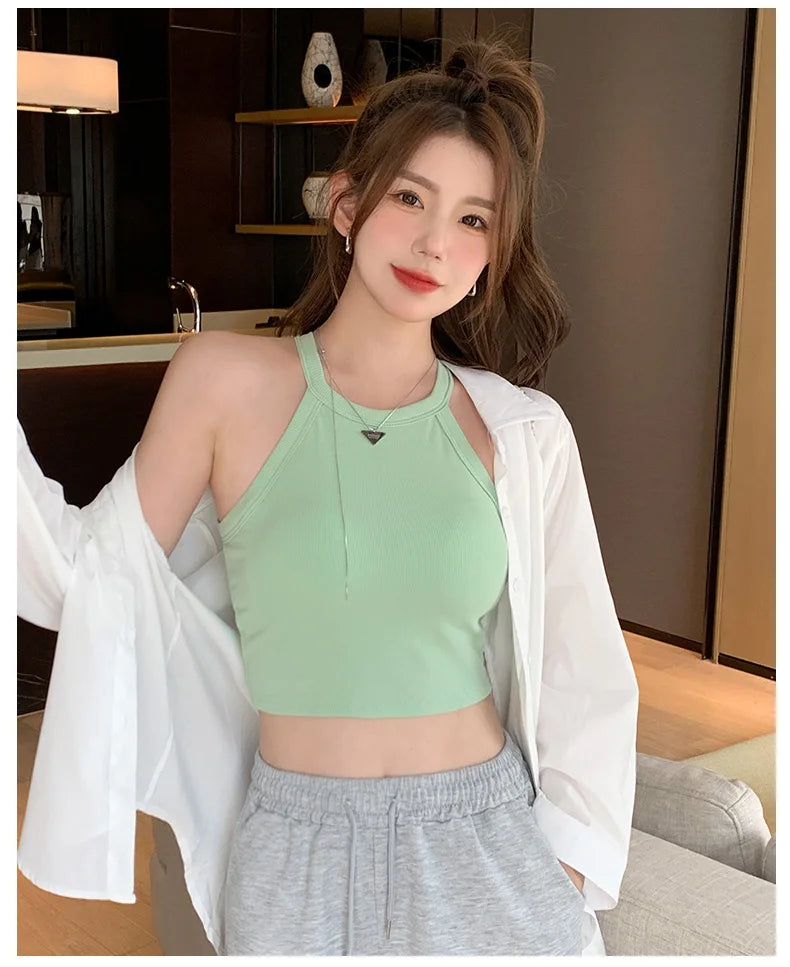 Woman wearing a green knitted camisole with a white shirt; showcasing soft cotton comfort and casual style.