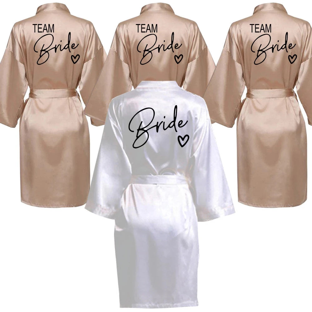 Team Bride satin robes in beige and white, featuring stylish lettering for bridal parties.