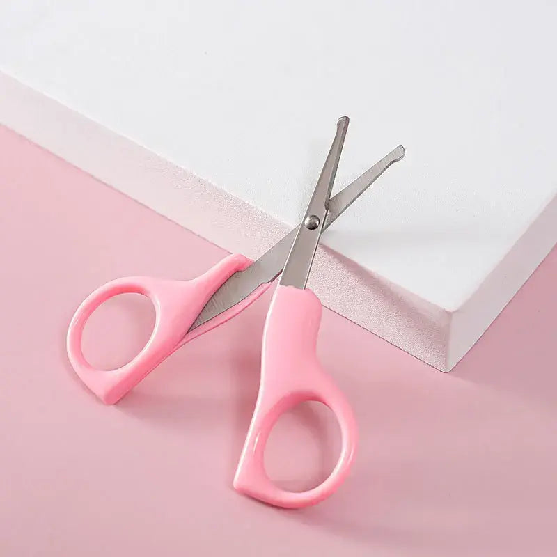 Pink children's scissors on a pink background, ideal for crafting and safe for kids.