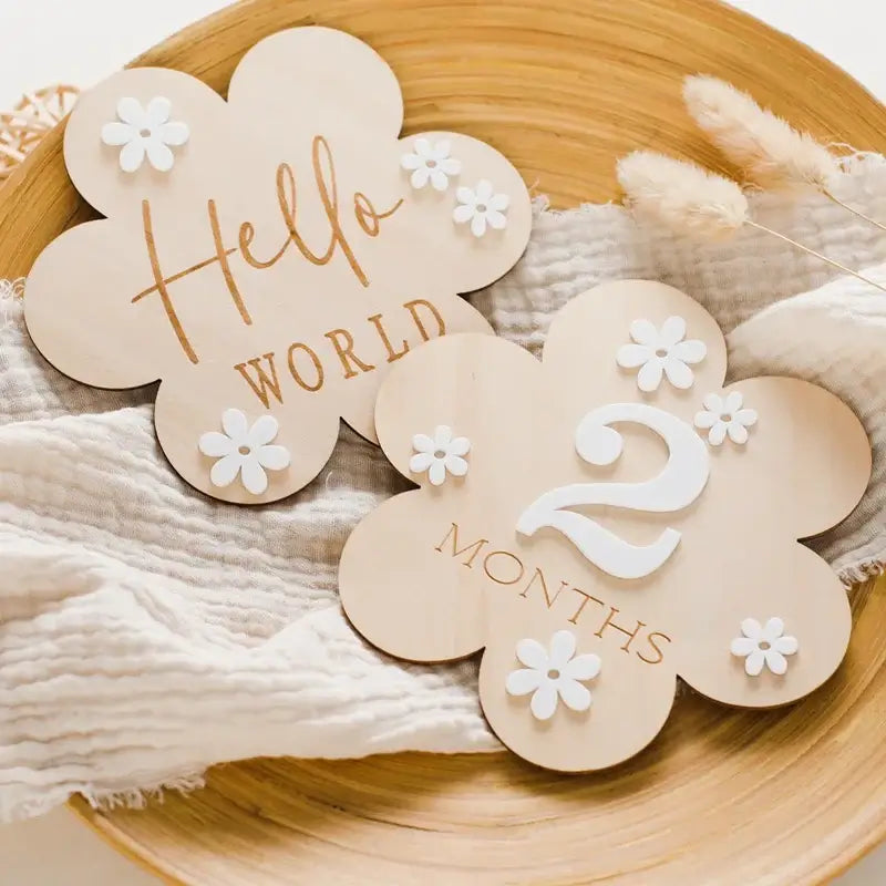 Wooden baby milestone markers in flower shape, featuring 'Hello World' and '2 Months', perfect for photo props.