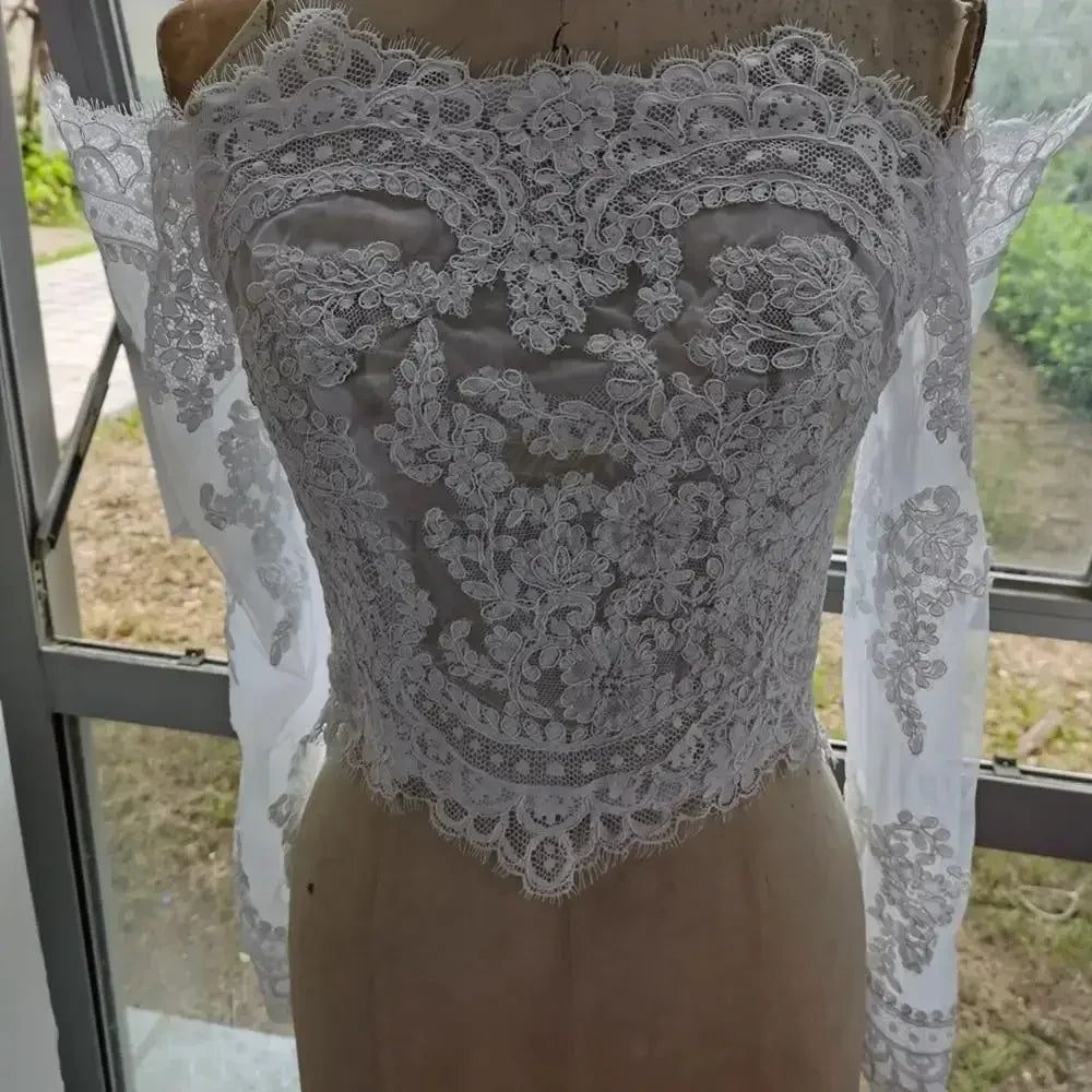 Lace off shoulder bridal jacket with intricate appliqued design and long sleeves, perfect for wedding attire.