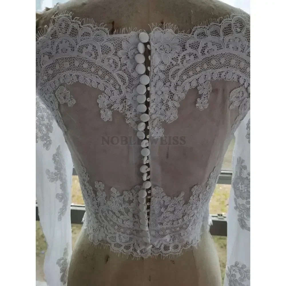 Back view of lace off-shoulder bridal jacket with intricate appliqué detailing and button closure, designed by Noble Weiss.