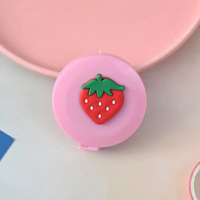 Cute pink tape measure with a strawberry design on top, perfect for crafting and home use.