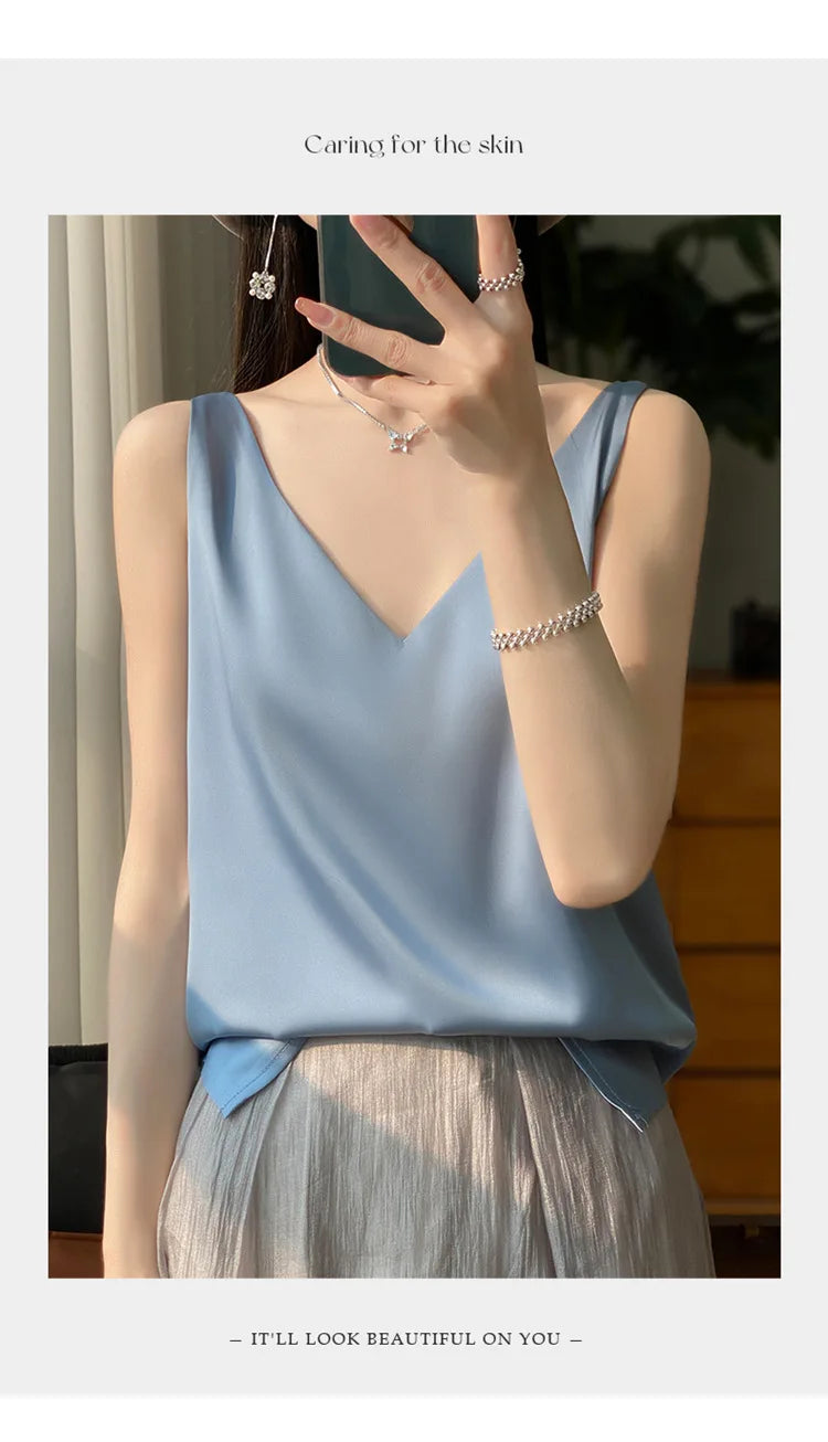 Woman wearing a blue satin V-neck camisole top with stylish jewelry and soft lighting, showcasing summer elegance.