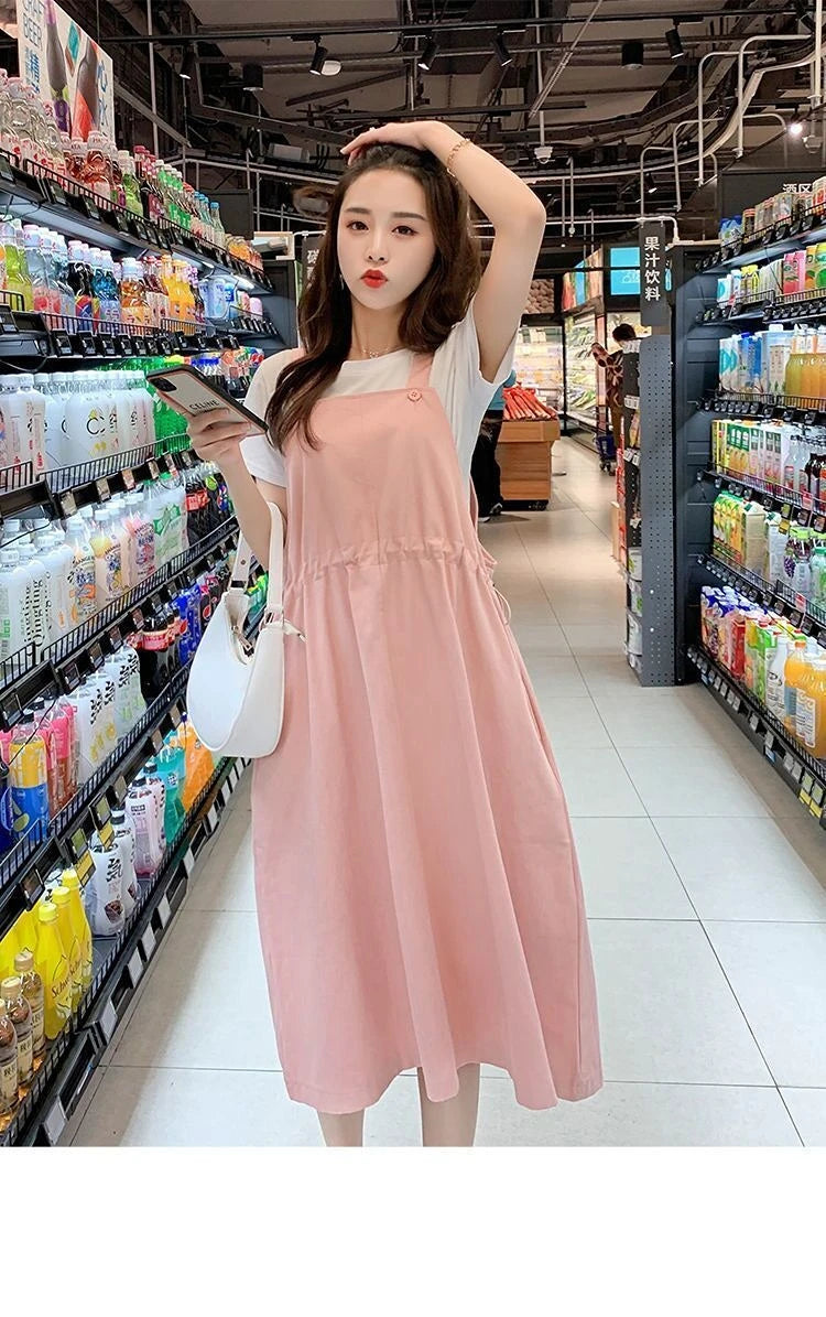 Woman in pink loose fit maternity dress shopping in a grocery store aisle, showcasing a casual and comfortable style.