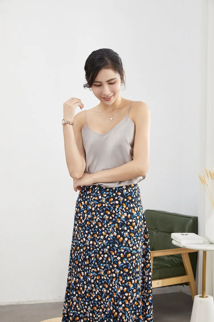 Woman wearing a beige satin camisole with a floral skirt, showcasing casual summer style.