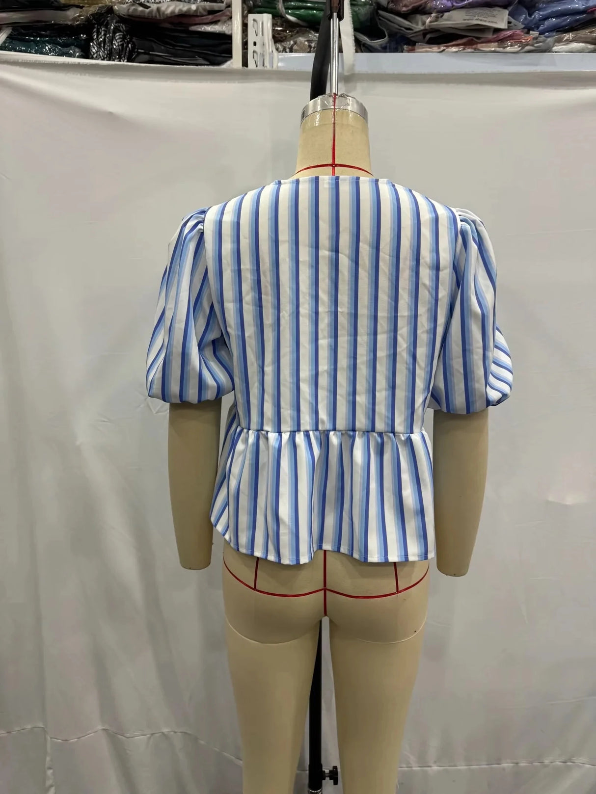 Back view of BowChic™ Stripe Lace-Up Blouse in blue and white stripes with peplum detail, showcasing short puff sleeves.