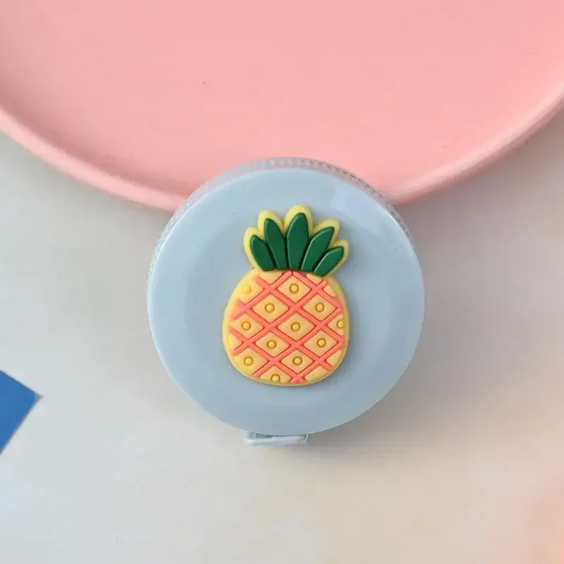 Cute pineapple-shaped tape measure on a round light blue background.