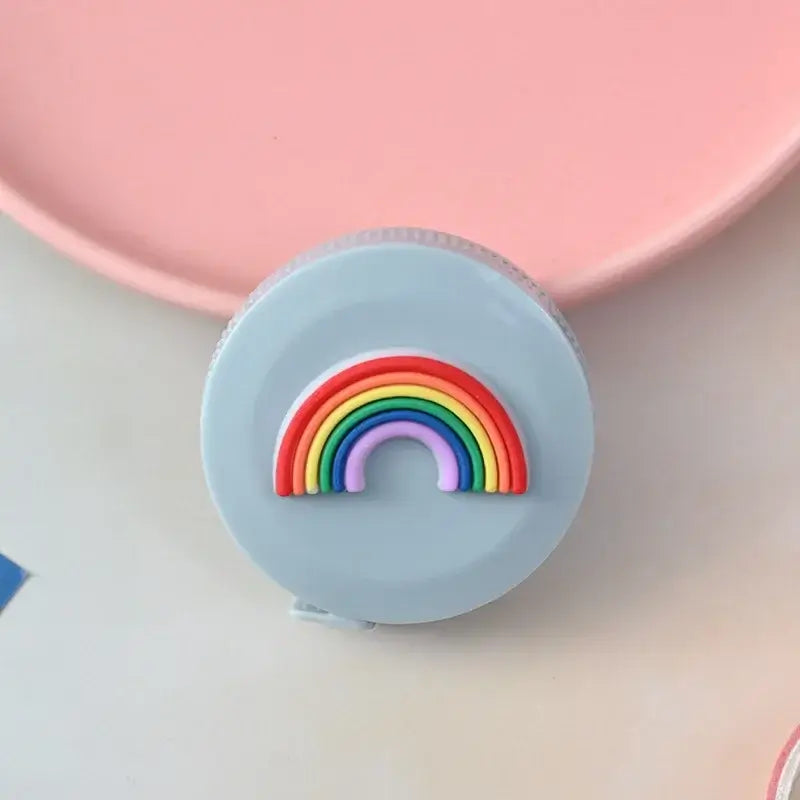 Cute round measuring tape with a colorful rainbow design on a light blue background.