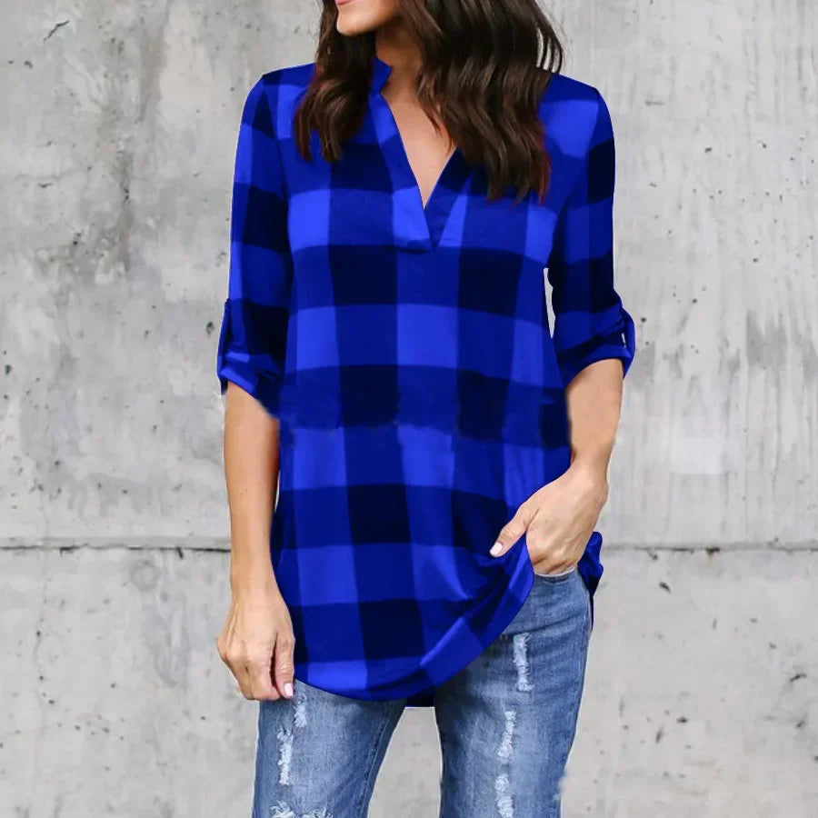 Woman wearing a blue plaid V-neck summer shirt, styled for casual beach outings, paired with distressed jeans.