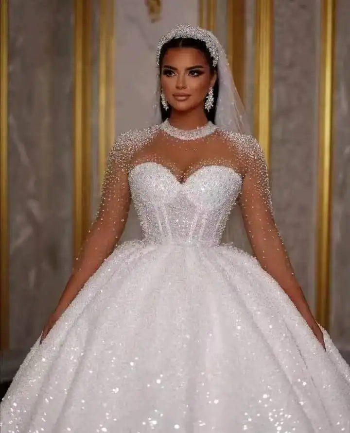 Elegant bride wearing a luxurious white ball gown wedding dress with lace and pearl details.