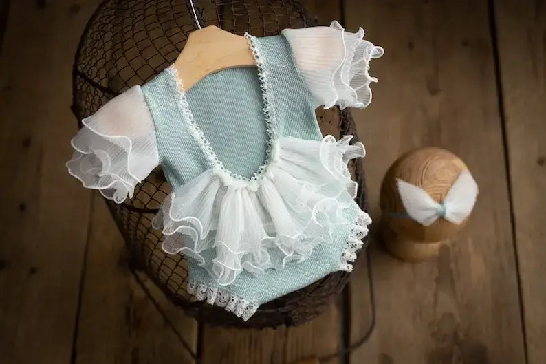 Newborn photography prop featuring a ruffled mint green romper with lace accents and a matching bow headband.