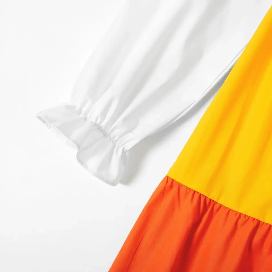 Close-up of long sleeve V-neck maternity dress with colorful pleated hem in yellow and orange.