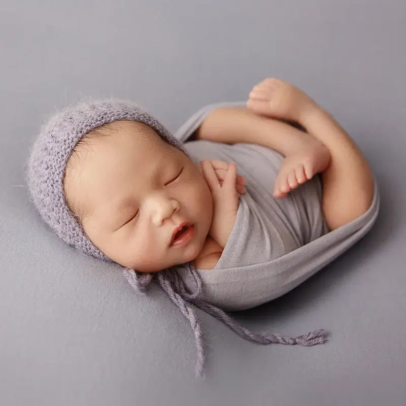 Newborn sleeping peacefully wrapped in soft blanket with knitted cap, perfect for photography and cozy comfort.
