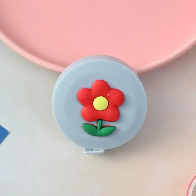 Cute round measuring tape with a red flower design on a gray background, perfect for children and home use.