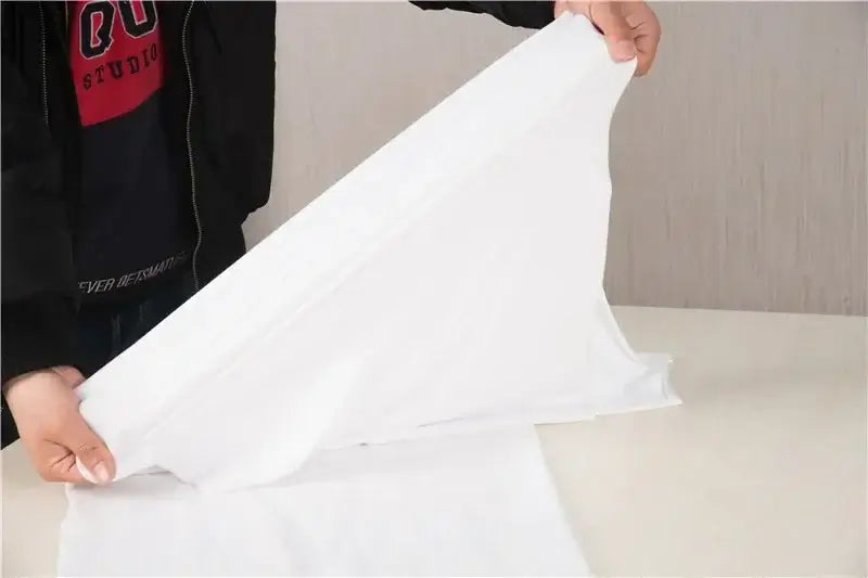 Folded white polyester blanket being prepared for a baby photo shoot backdrop, suitable for unisex infants.
