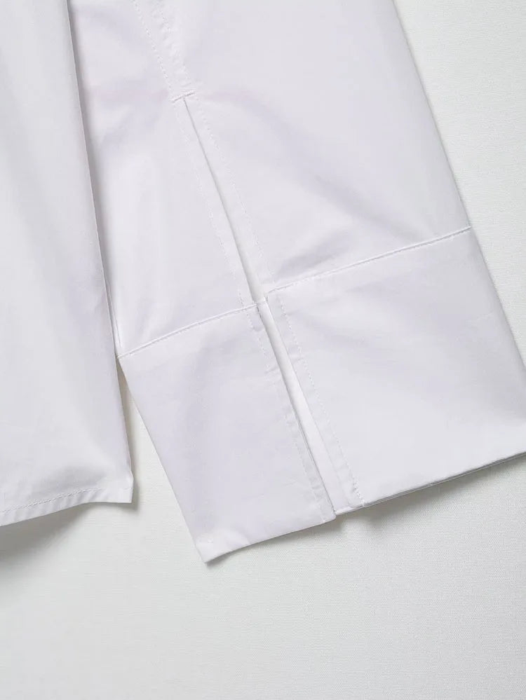 Close-up of the sleeve of an elegant white embroidered shirt, showcasing neat stitching and fabric details.
