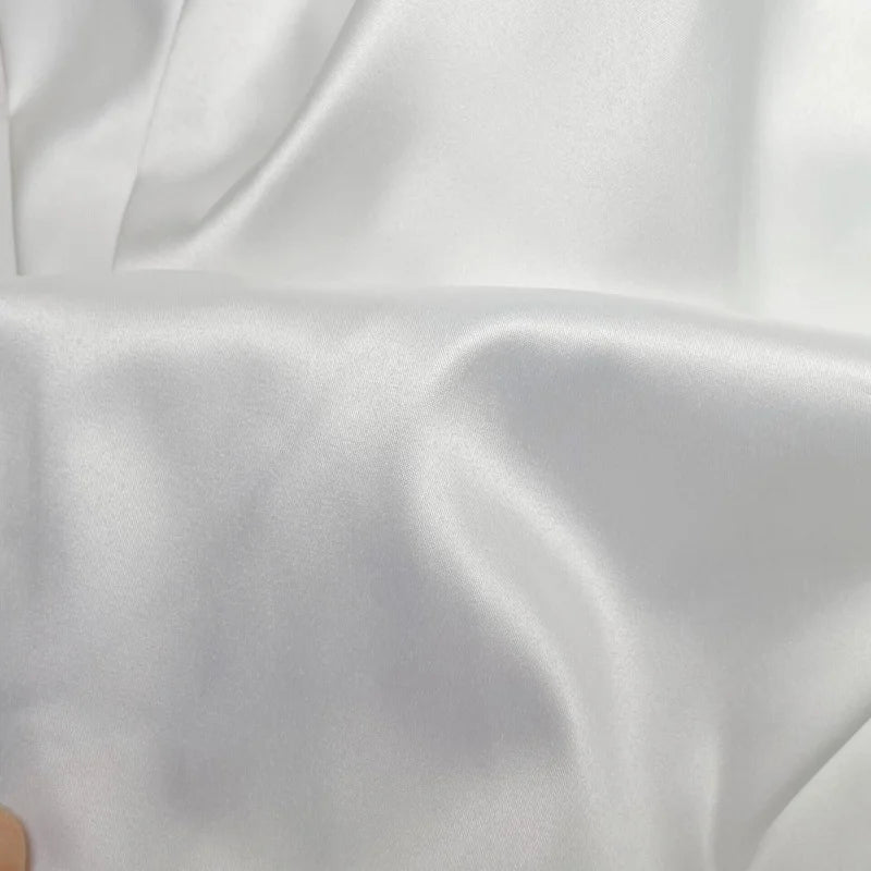 Close-up of luxurious white crystal satin fabric, ideal for elegant wedding dresses and formal attire.