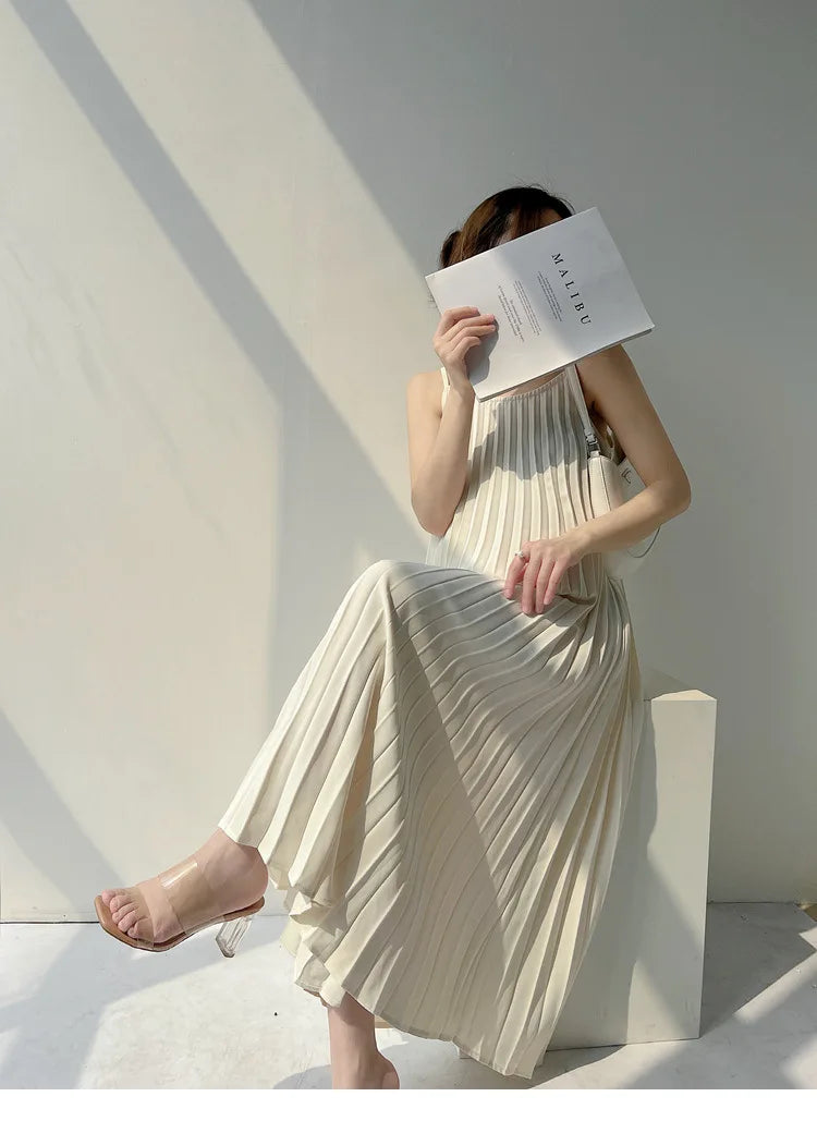 Woman in a pleated chiffon dress sitting with a book, showcasing a stylish mid-calf length look.