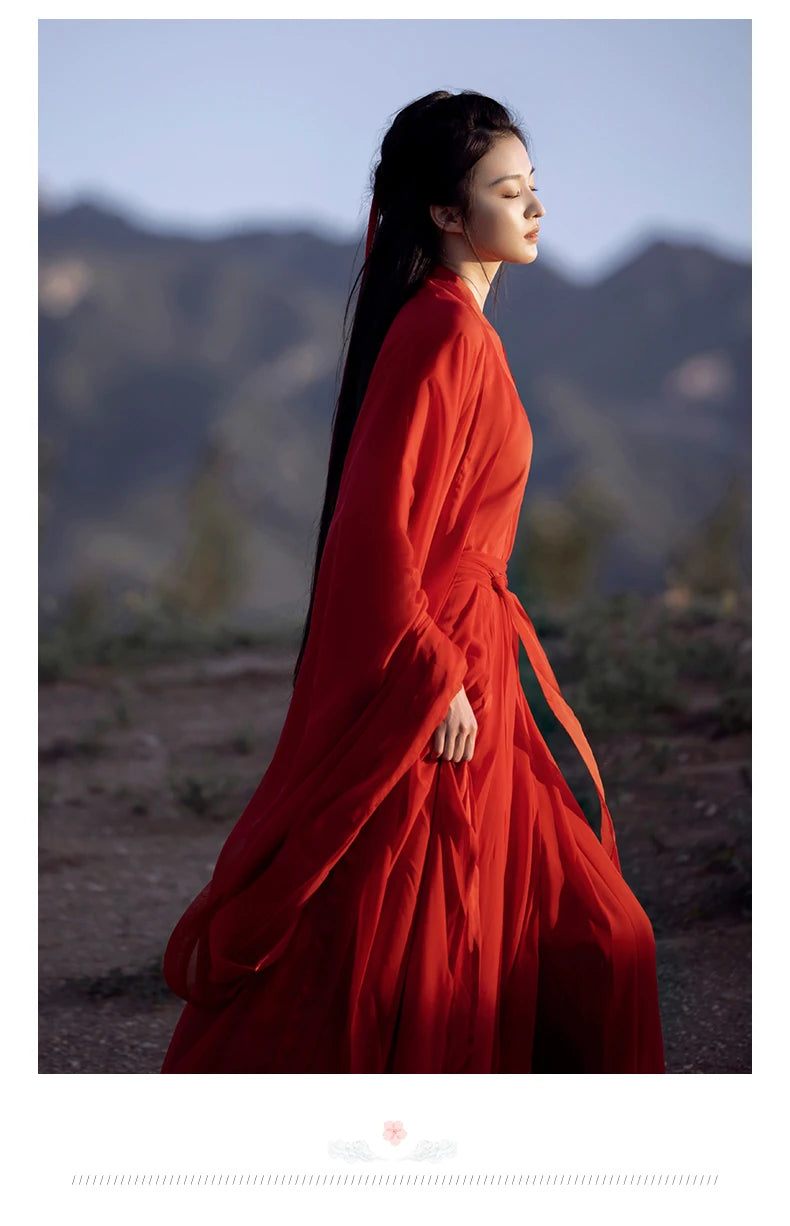 Elegant woman in a flowing red Hanfu dress against a scenic backdrop, showcasing traditional Chinese cosplay costume.