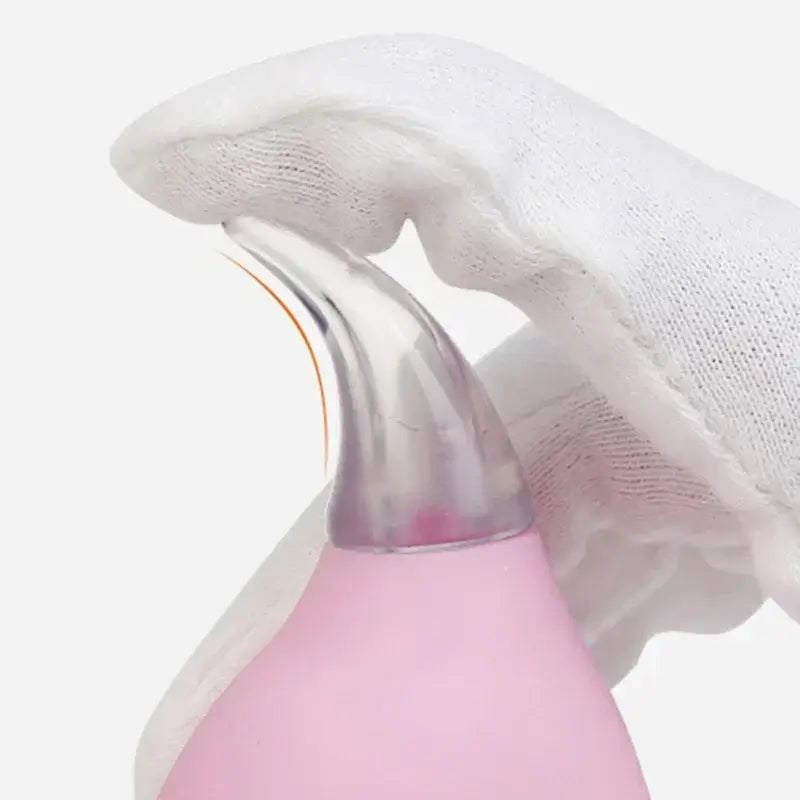Close-up of a pink nasal aspirator held in a gloved hand, designed for baby care and hygiene.