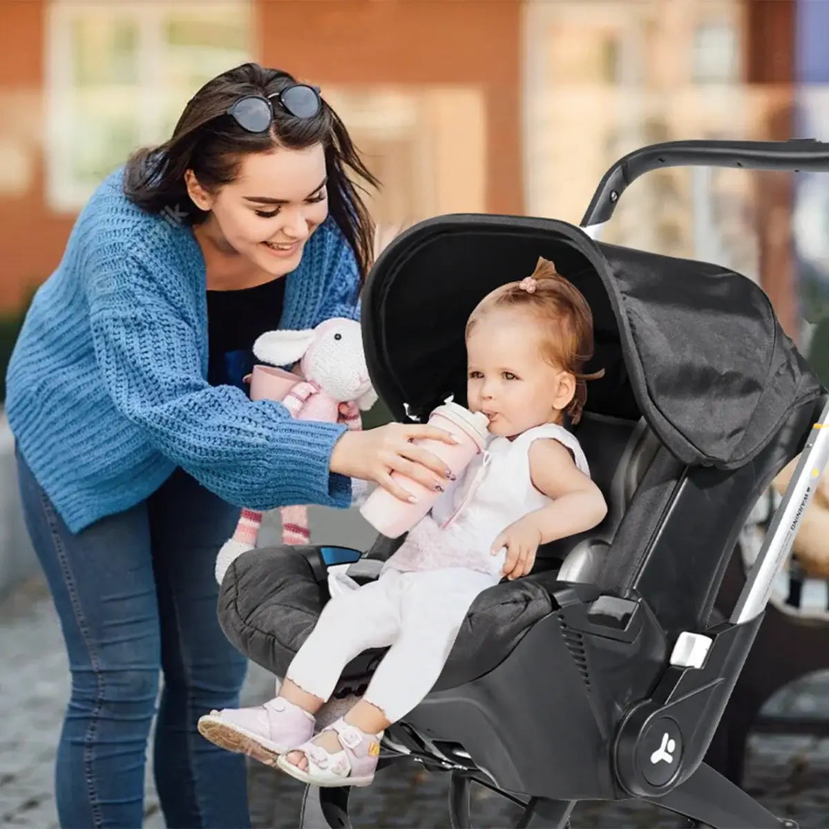 A mother feeding her toddler in a stylish baby stroller with a metal frame, perfect for ages 0-2 years.