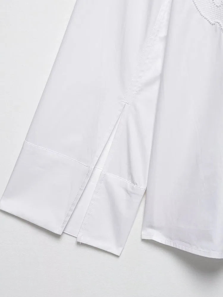 Detail of the long sleeve white blouse showcasing elegant embroidery and stylish side slits.
