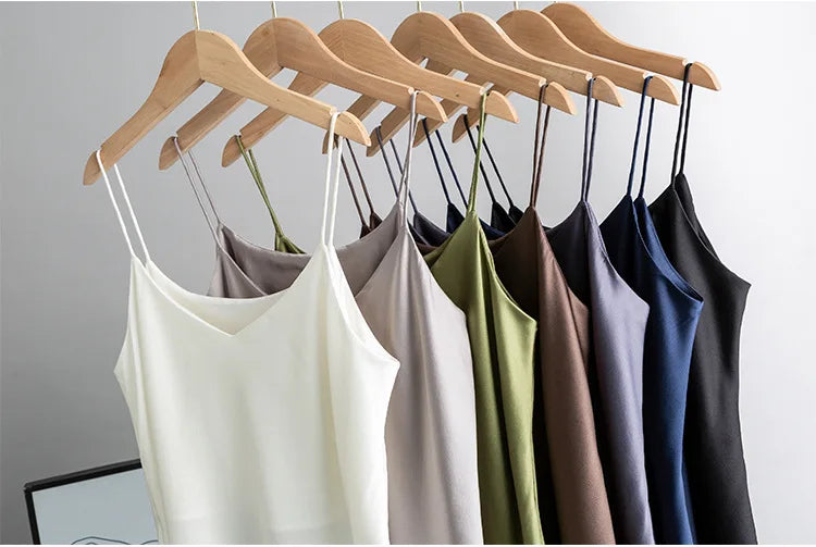 Various colors of BandeauSilk™ double-layer mulberry silk camisoles hanging on wooden hangers.