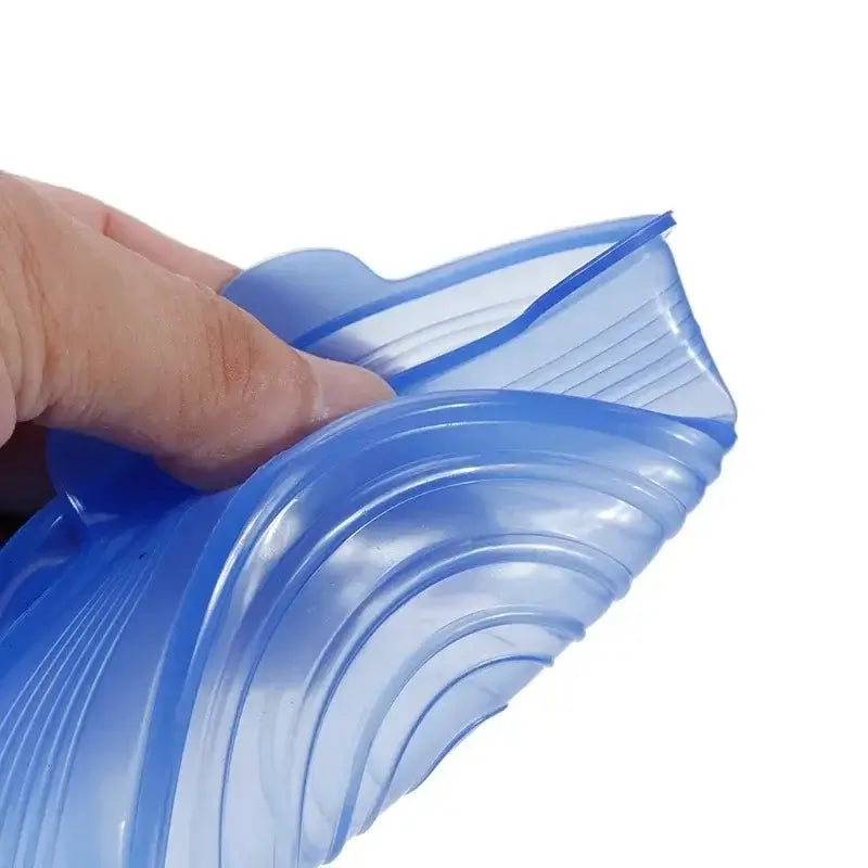 Close-up of a hand holding a flexible blue silicone food cover, showcasing its stretchy design for airtight sealing.