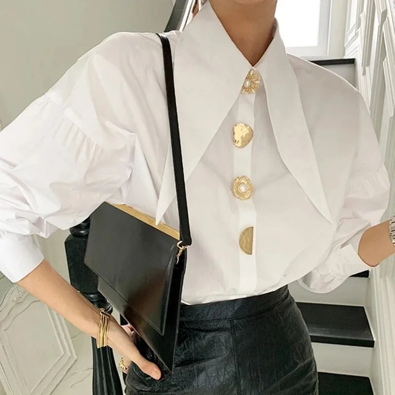 Model wearing a chic white PearlEdge™ shirt with pearl buttons, paired with a black handbag in a stylish setting.